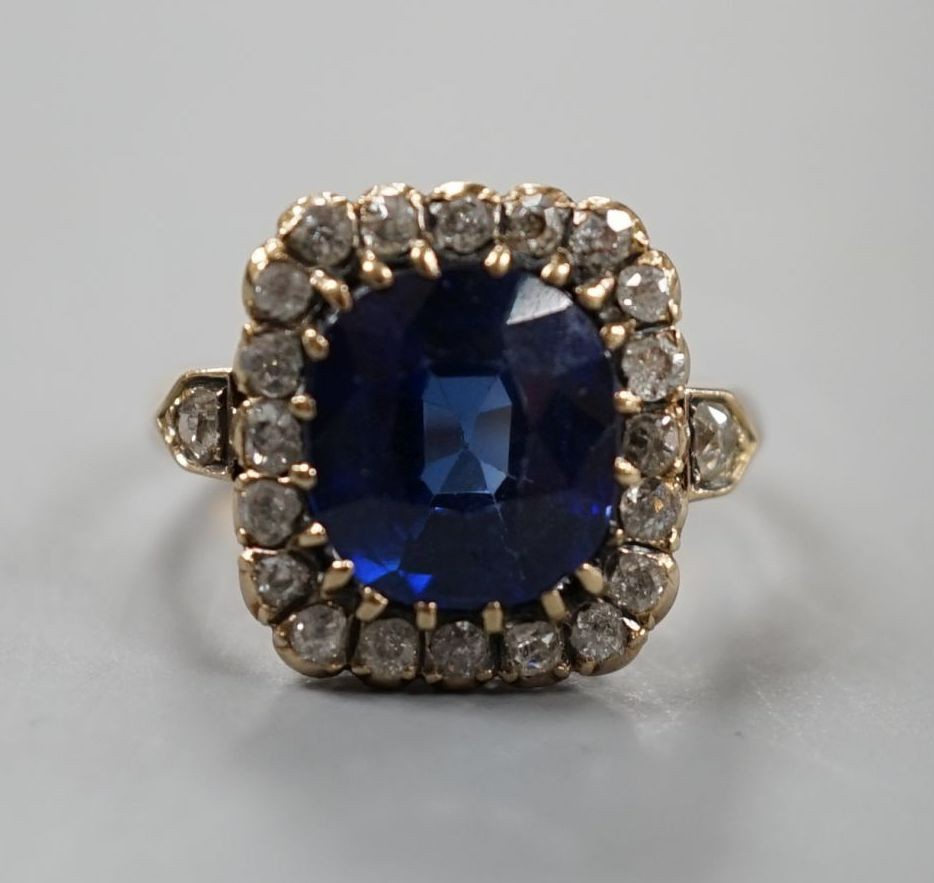 An early 20th century yellow metal, synthetic sapphire and old cut diamond set rectangular cluster ring, size N, gross weight 4.6 grams, with diamond set shoulders.